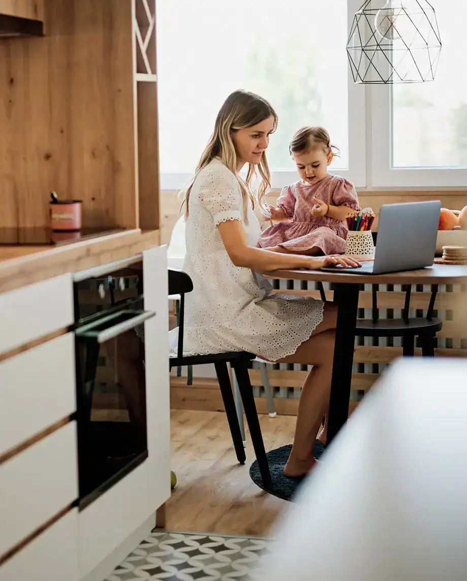 Family working from home with laptop in cozy kitchen setting.