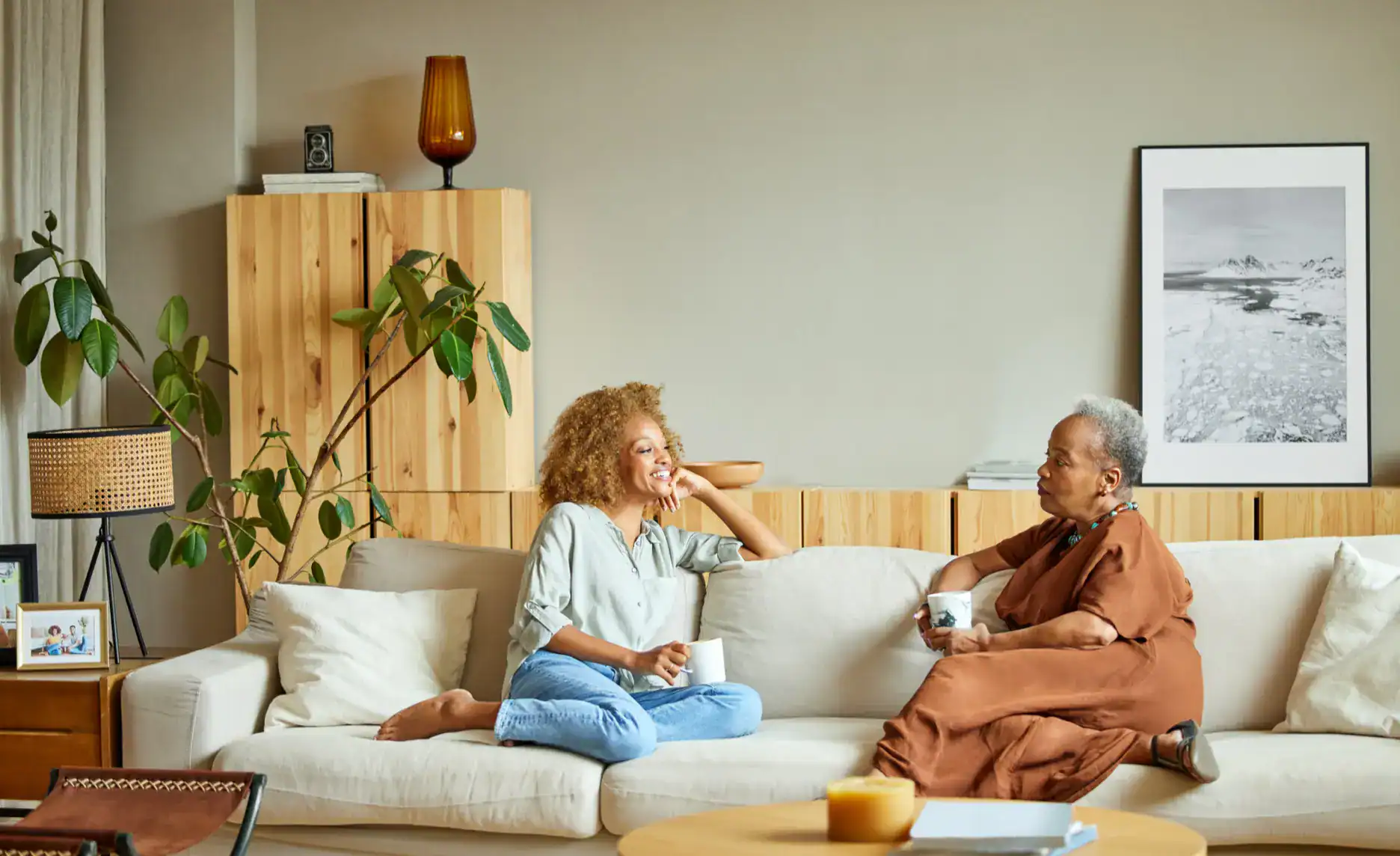 Cozy living room featuring two women relaxing and chatting on a modern sofa.