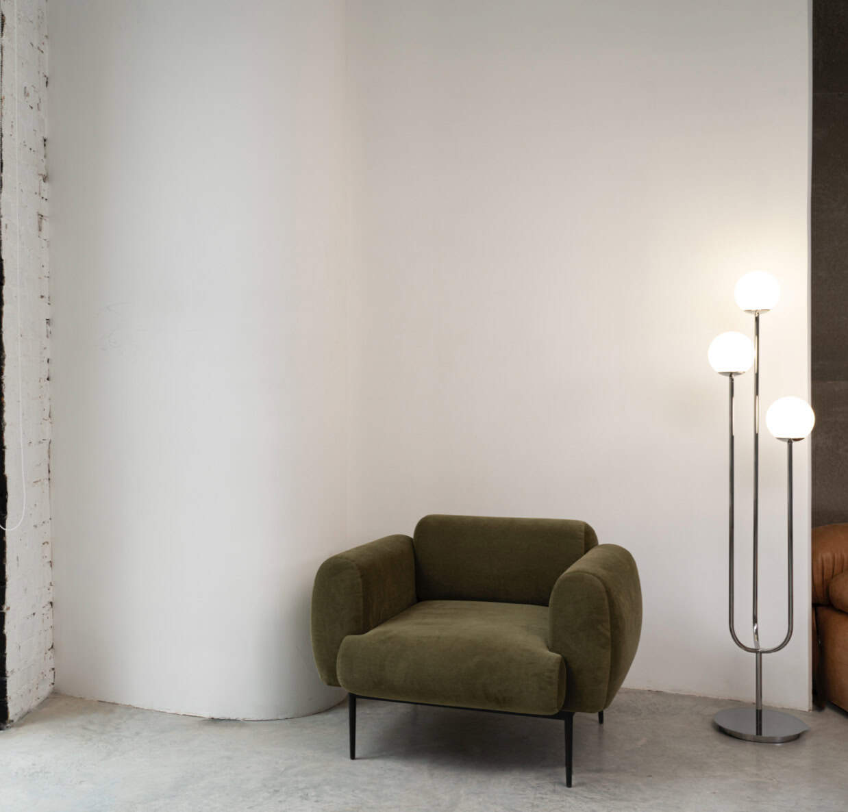 Olive green modern armchair with sleek black legs in a minimalist living space.