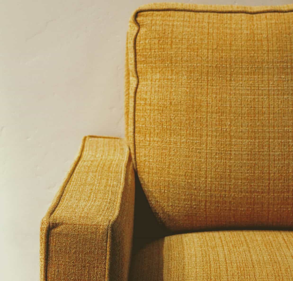 Elegant mustard yellow sofa with textured fabric and sleek design.