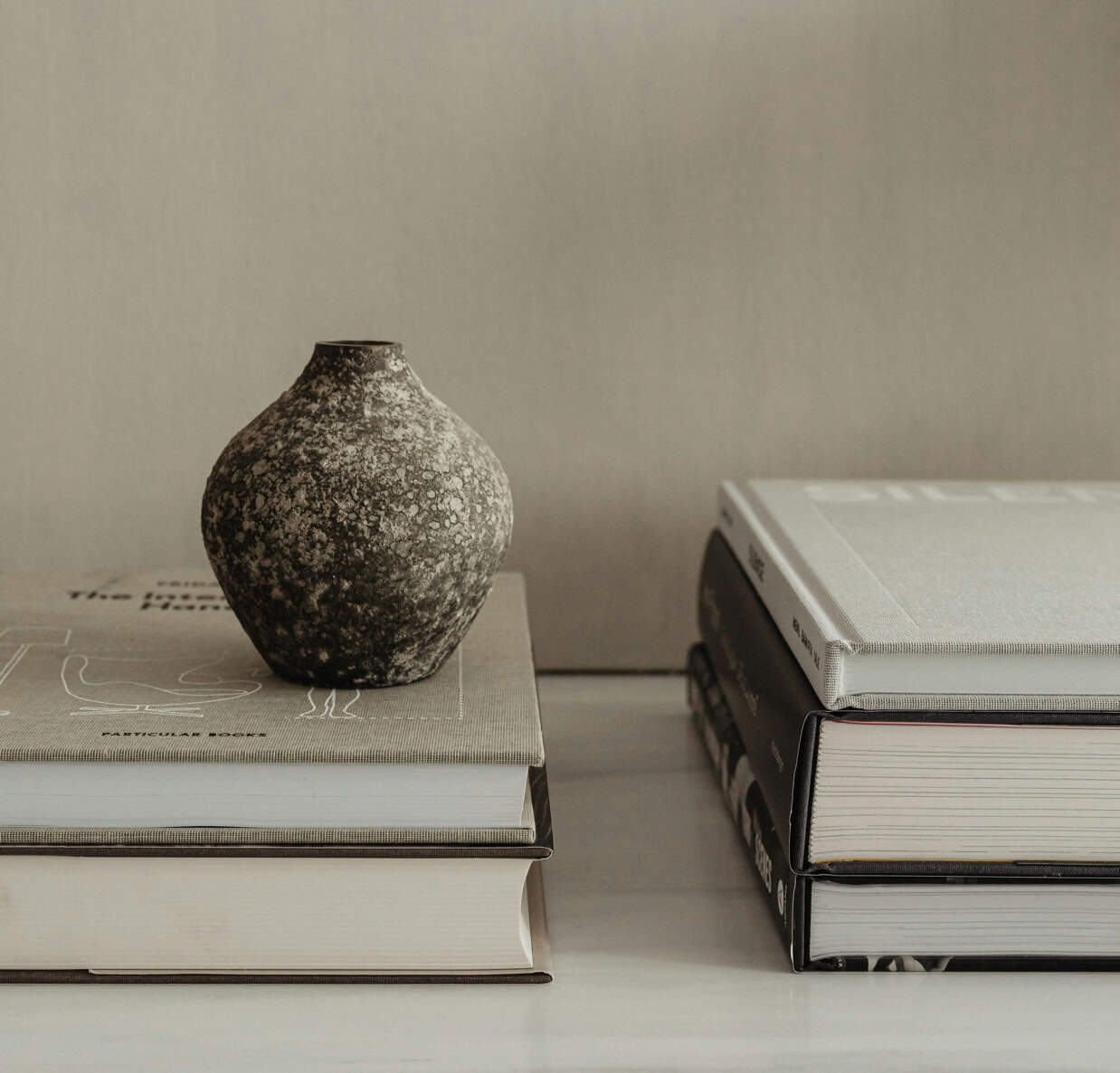 Ceramic vase placed on stacked books, showcasing modern home decor and interior design.