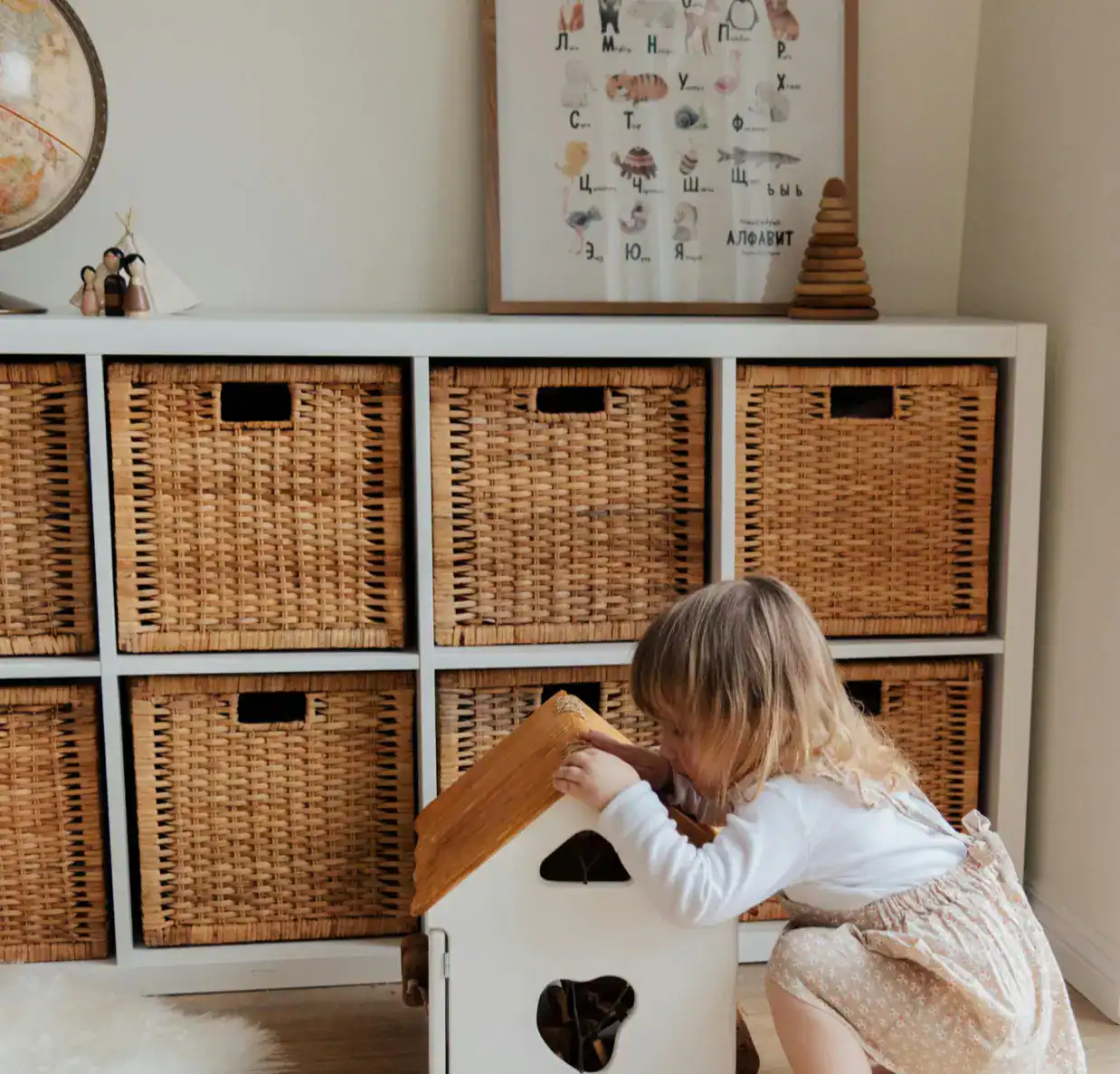 Child playing with a wooden house toy in a cozy, organized home setting.