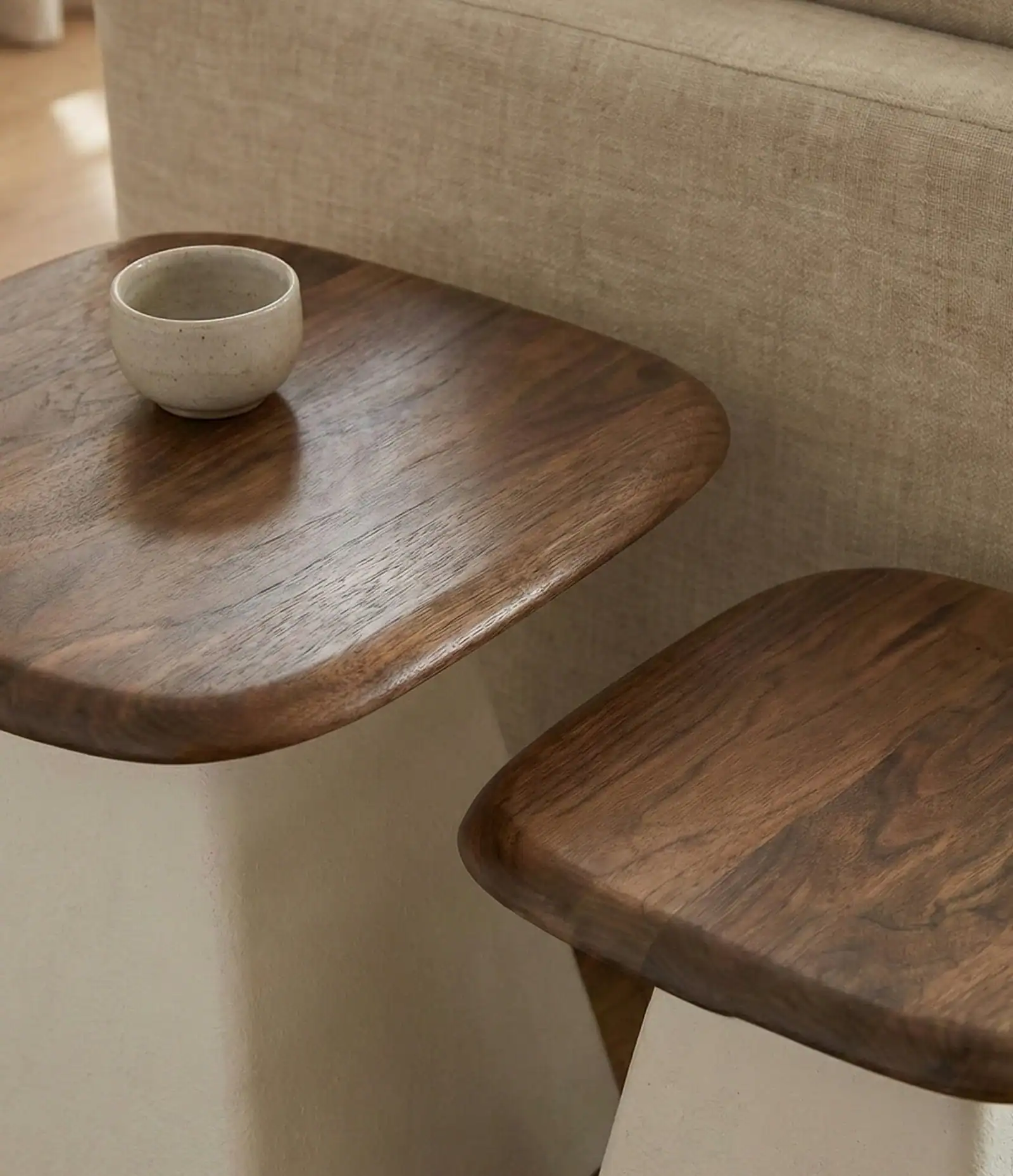 Wooden side table and stool with ceramic cup, showcasing natural wood craftsmanship and modern home.
