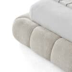Modern Novelda Bed with upholstered base and white bedding for stylish bedroom decor.