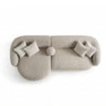 Modern beige sofa with round ottoman and decorative pillows.